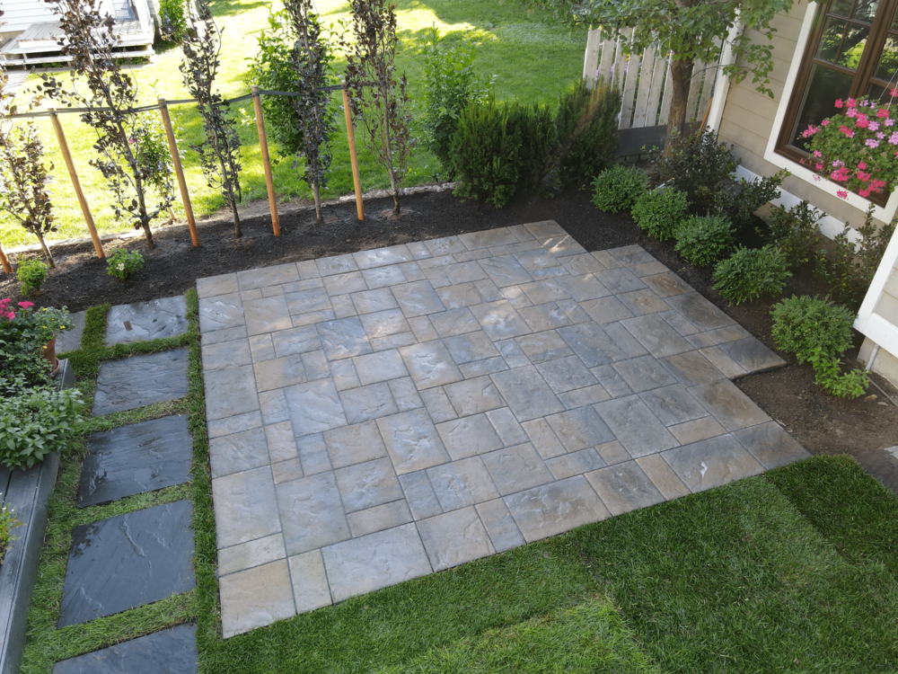 A square patio made out of brown, grey and orange stones.